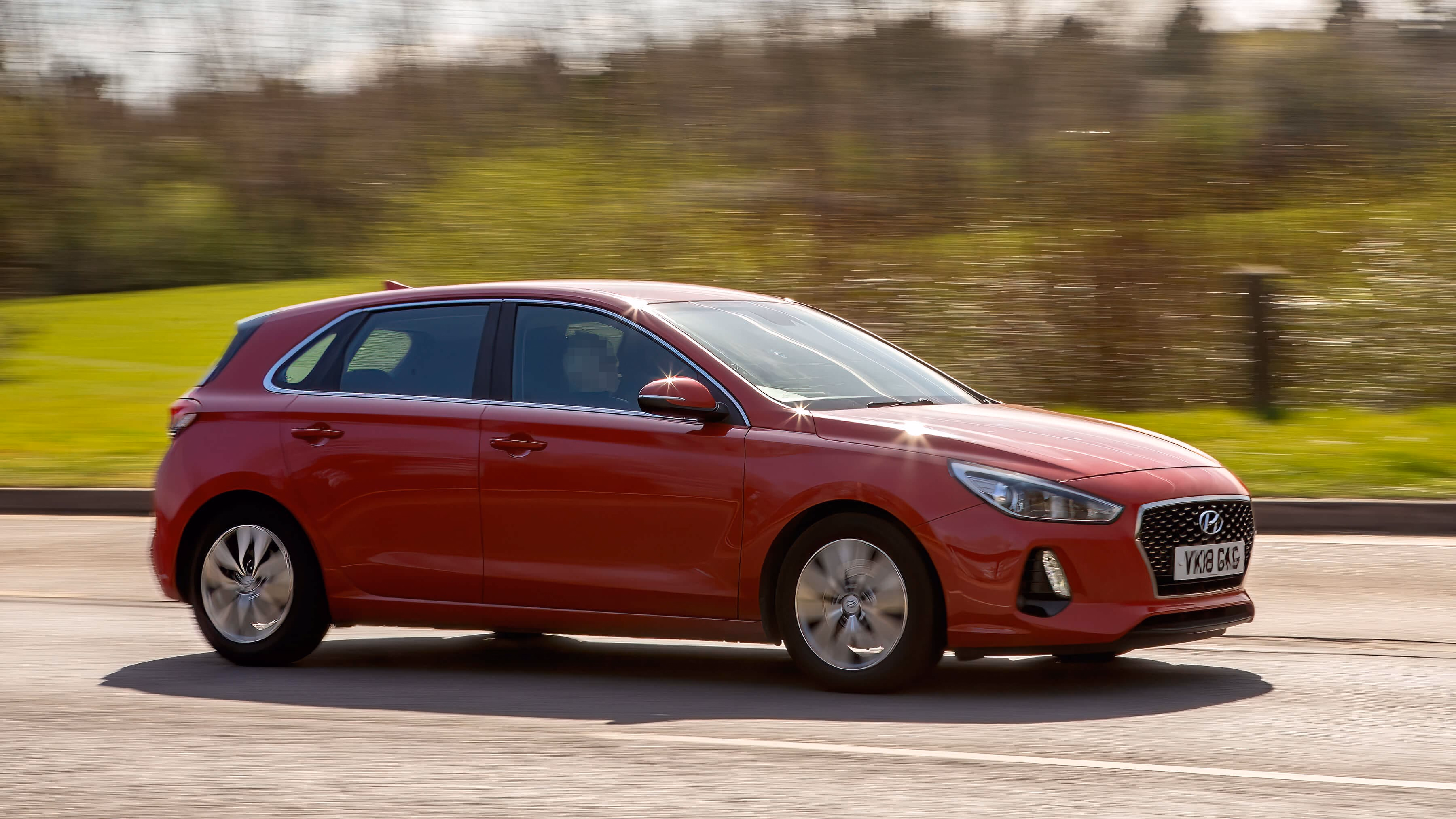 Czerwony hatchback Hyundai i30 jadący drogą