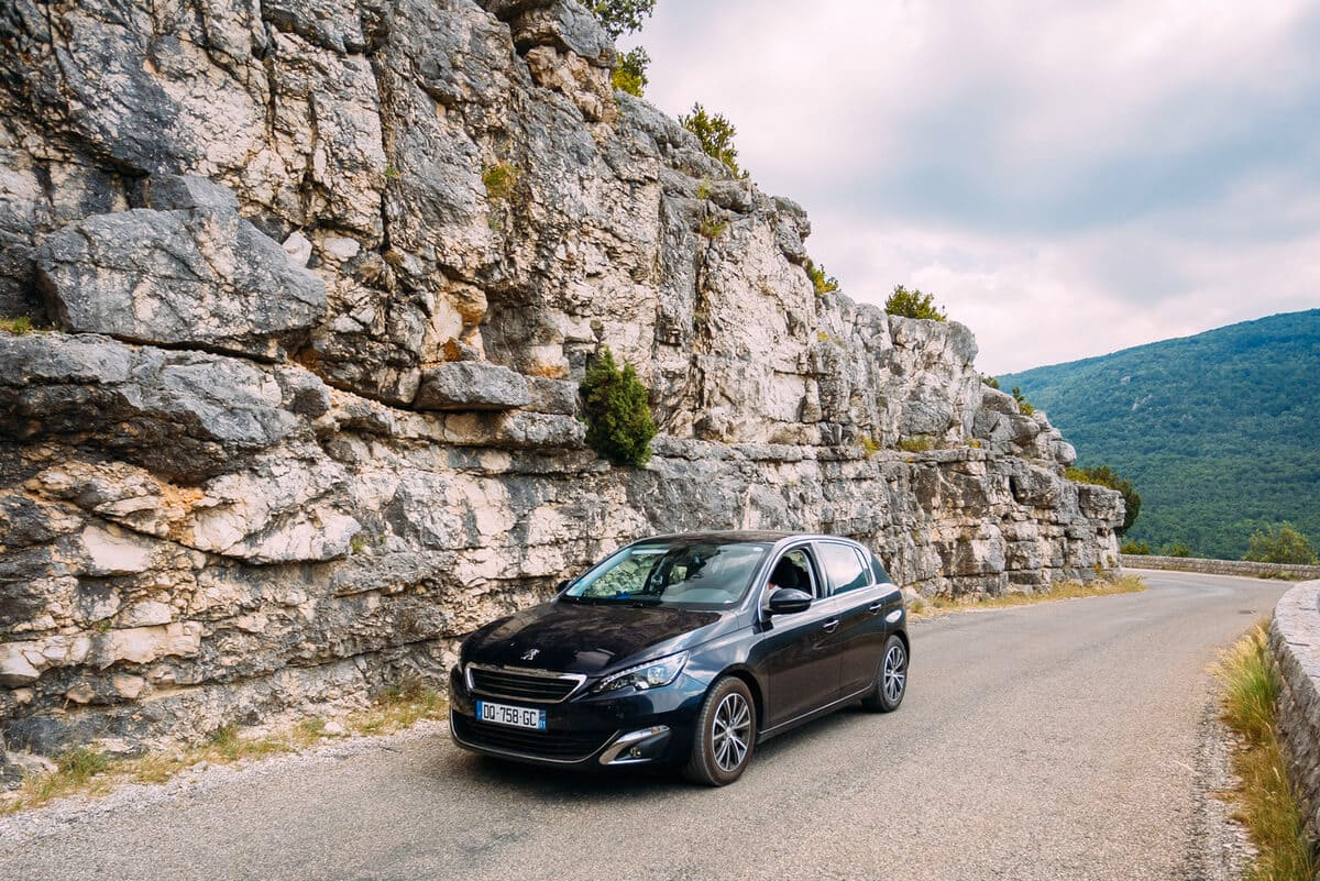 Czarny hatchback Peugeot 308 na drodze w górach