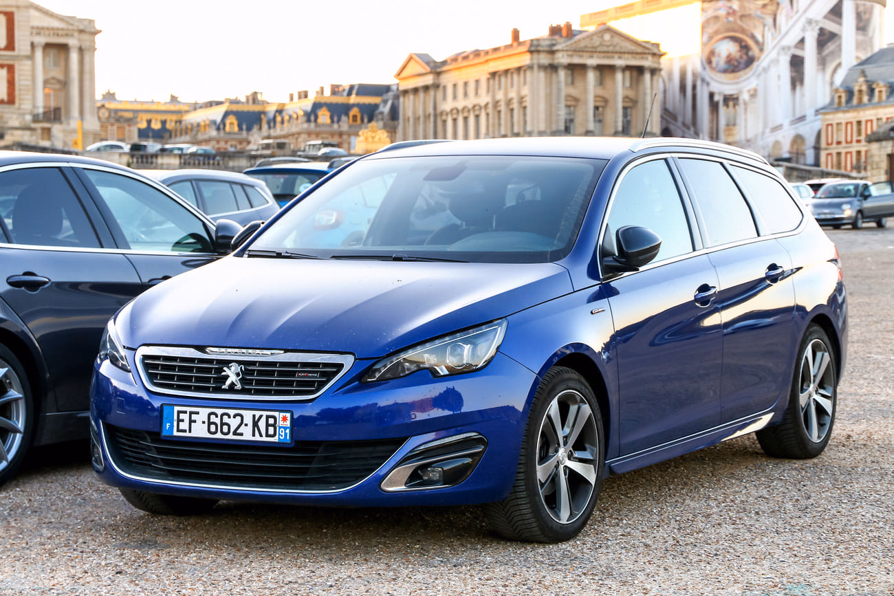 Niebieski Peugeot 308 SW zaparkowany w mieście